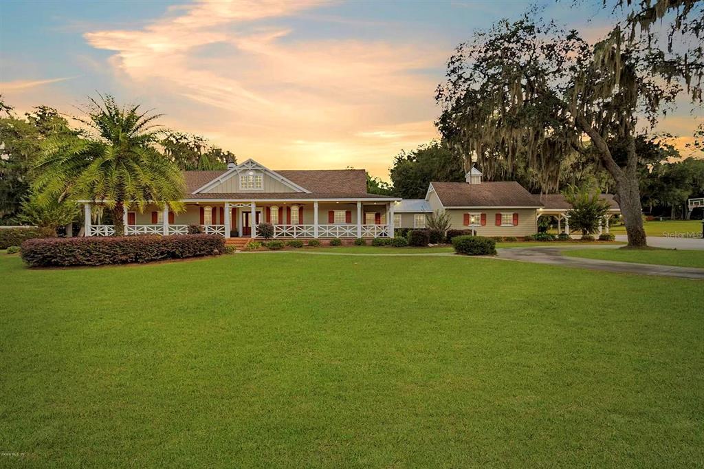 a front view of a building with garden and trees
