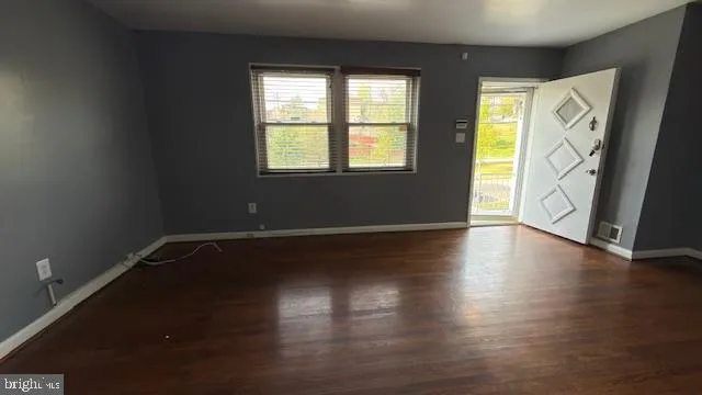 a view of an empty room with wooden floor and a window