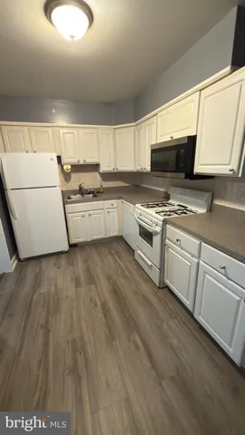 a kitchen with cabinets a sink and white appliances