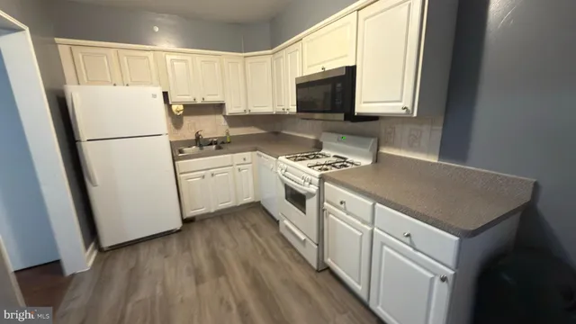 a kitchen with a sink a refrigerator a microwave a stove and cabinets