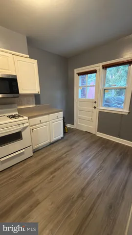 a view of a kitchen with wooden floor and electronic appliances