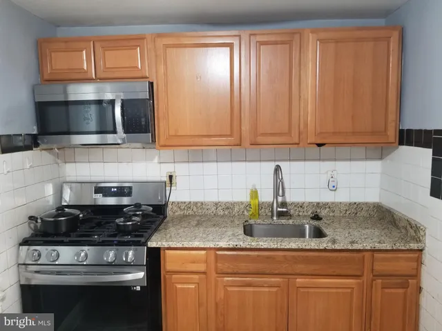 a kitchen with stainless steel appliances granite countertop a sink a stove and a microwave