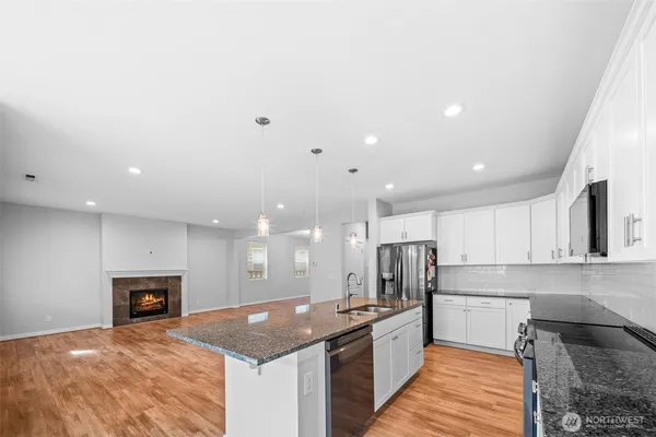 a kitchen with stainless steel appliances granite countertop a sink refrigerator and cabinets