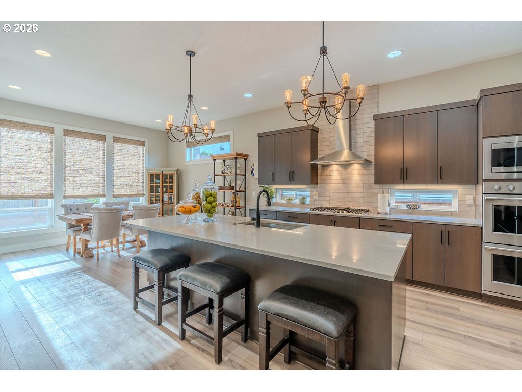 38408 Juniper Street Sandy, OR 97055 - Photo 22 of 47 a kitchen with stainless steel appliances kitchen island granite countertop a table chairs in it and wooden floors