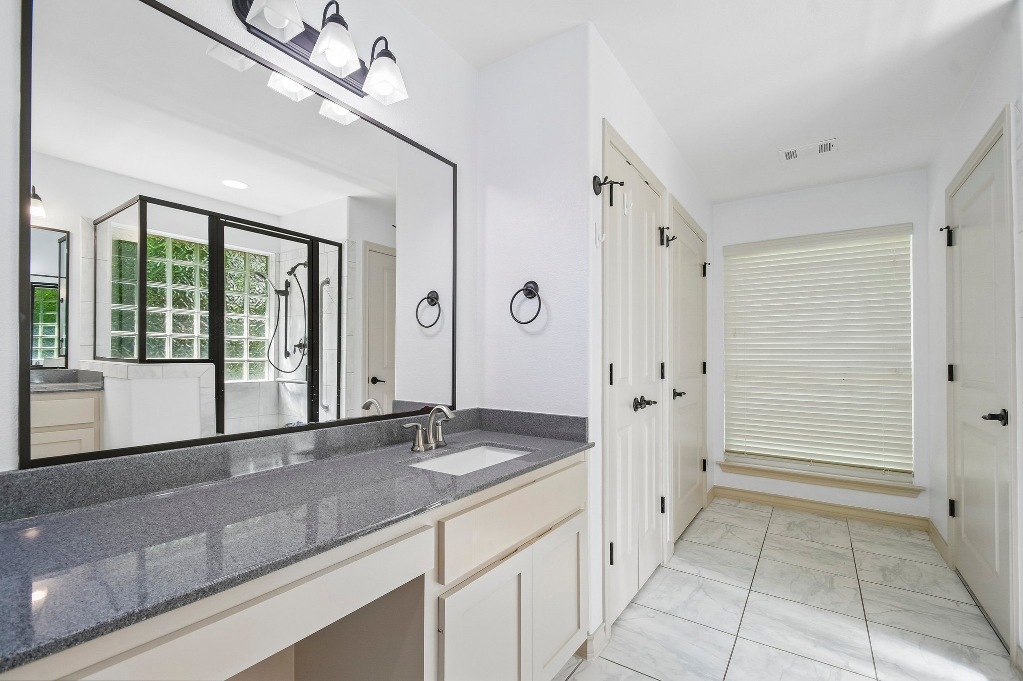 307 West 4th Street Elgin, TX 78621 - Photo 19 of 40 Vanity with gray speckled countertop and integrated sink, complemented by a large framed mirror