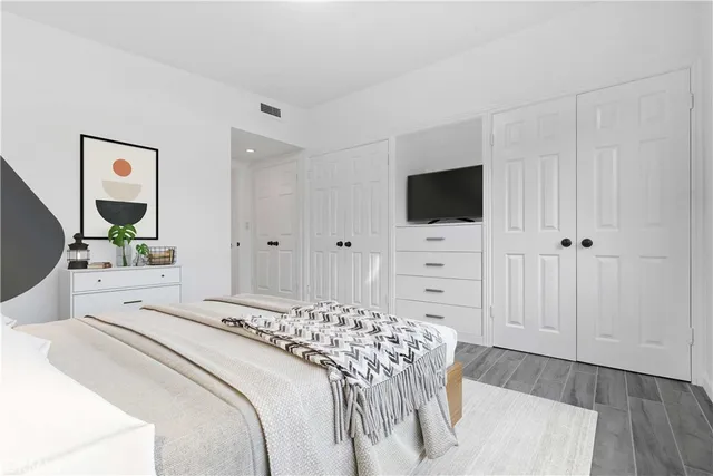 a bedroom with a bed a flat tv screen and a potted plant