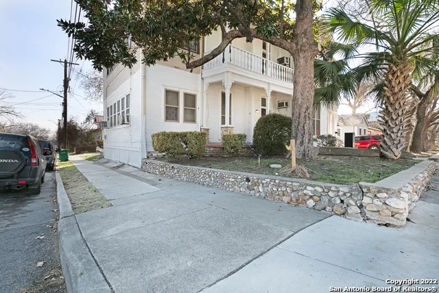 a view of a white house with a large tree