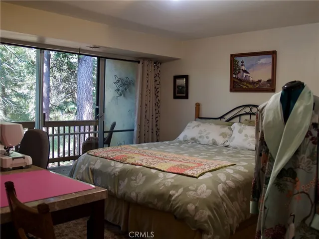 a bedroom with a bed a desk and chair with window