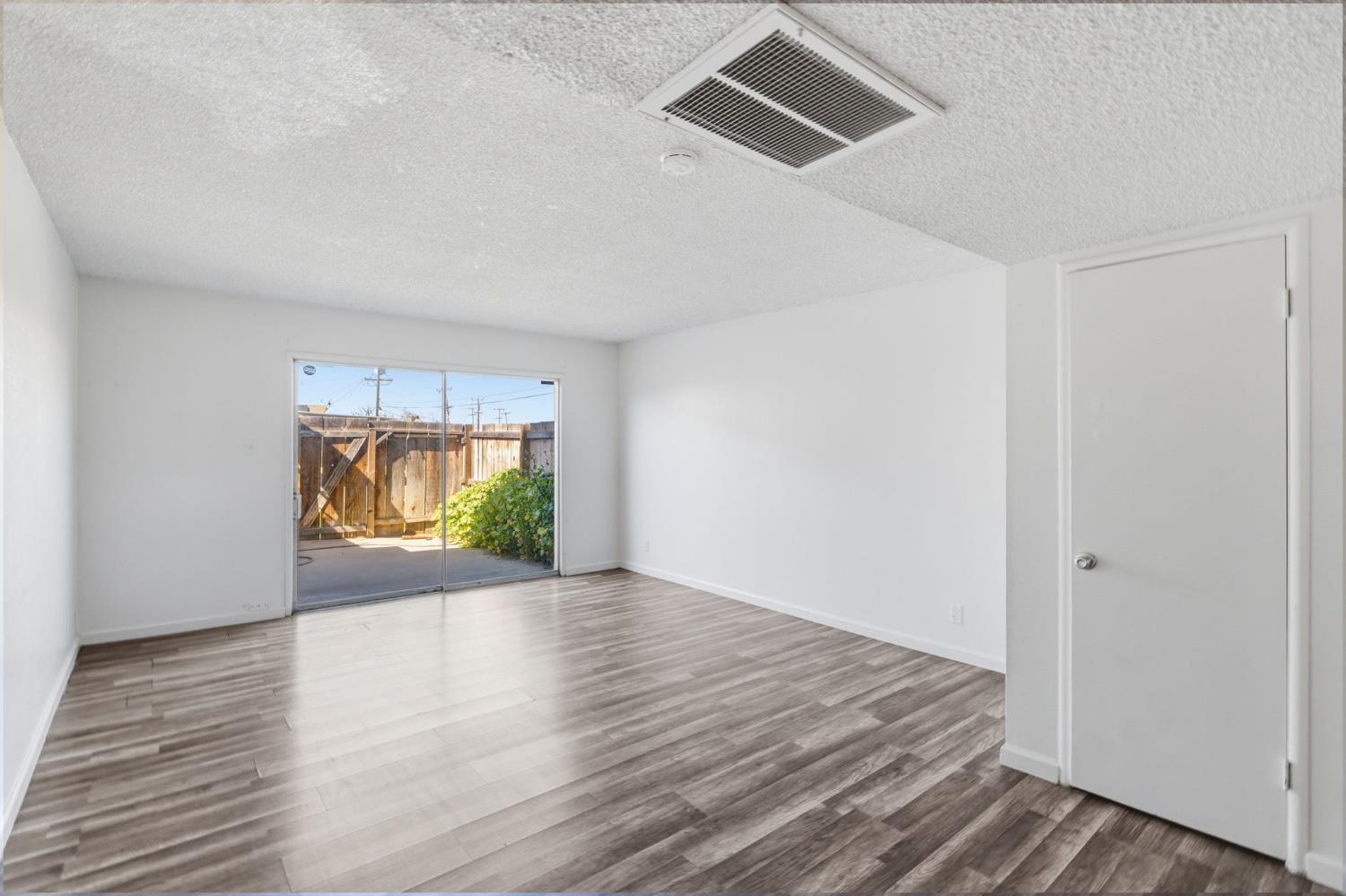 175 South 19th Avenue Lemoore, CA 93245 - Photo 11 of 42 an empty room with wooden floor and window