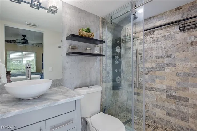 a bathroom with a granite countertop sink a toilet and shower