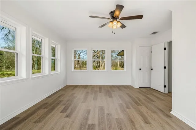 a view of an empty room with a window and wooden floor