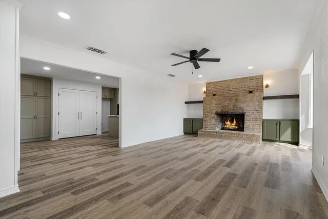 an empty room with wooden floor a fireplace and a window