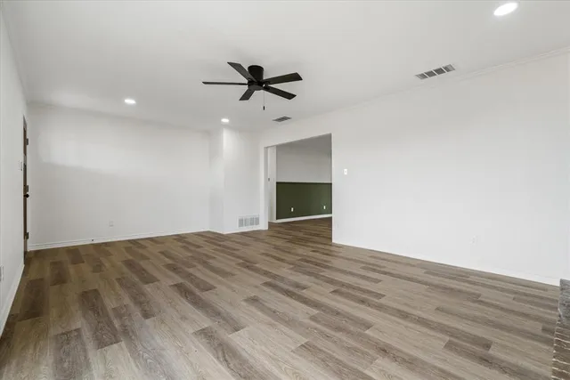 a view of empty room with wooden floor and ceiling fan
