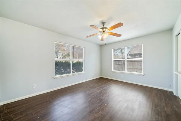 a view of an empty room with a window and wooden floor