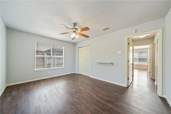 a view of an empty room with a window and wooden floor