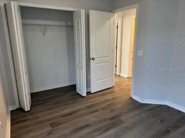 a view of a hallway with wooden floor and closet