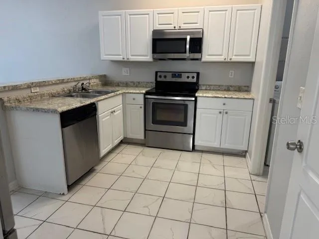 a kitchen with stainless steel appliances a sink dishwasher stove and white cabinets