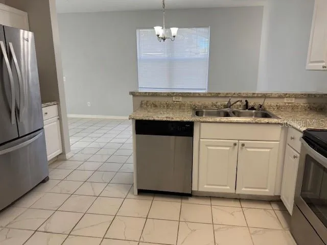 a kitchen with white cabinets a sink and a stove with a dining table