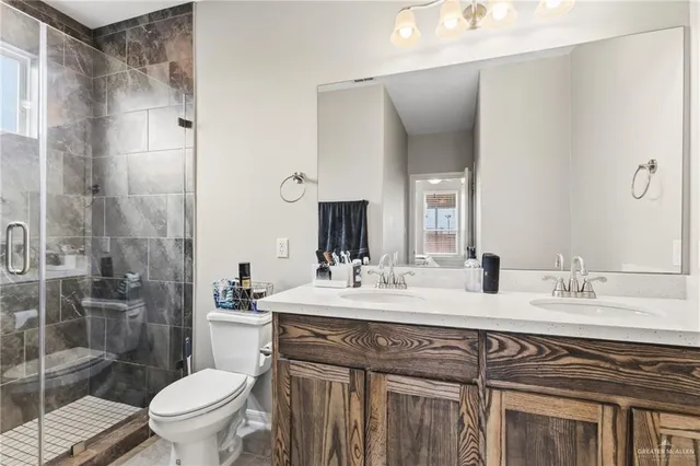 a bathroom with a granite countertop sink a toilet a mirror and shower