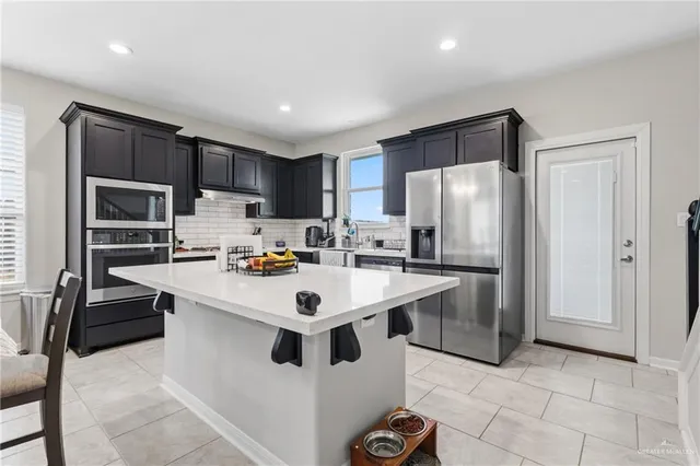 a kitchen with kitchen island a sink appliances and cabinets