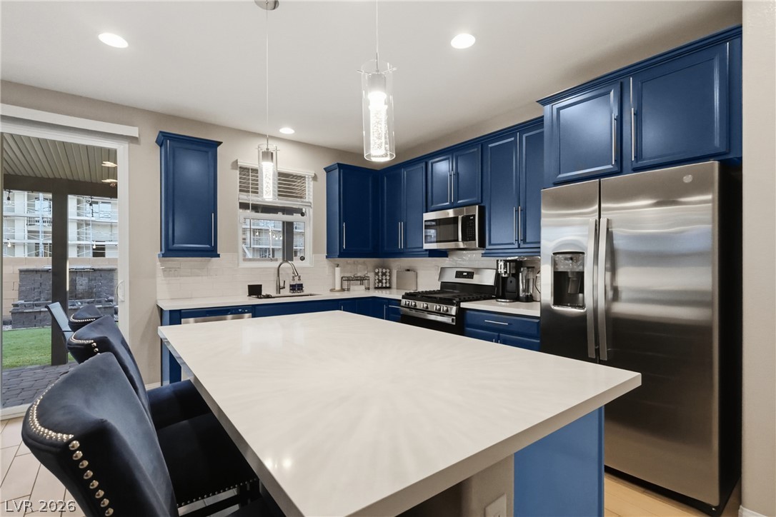 1921 Miller Ridge Avenue North Las Vegas, NV 89031 - Photo 7 of 26 This modern kitchen features rich blue cabinetry, sleek stainless steel appliances, and ample counter space.