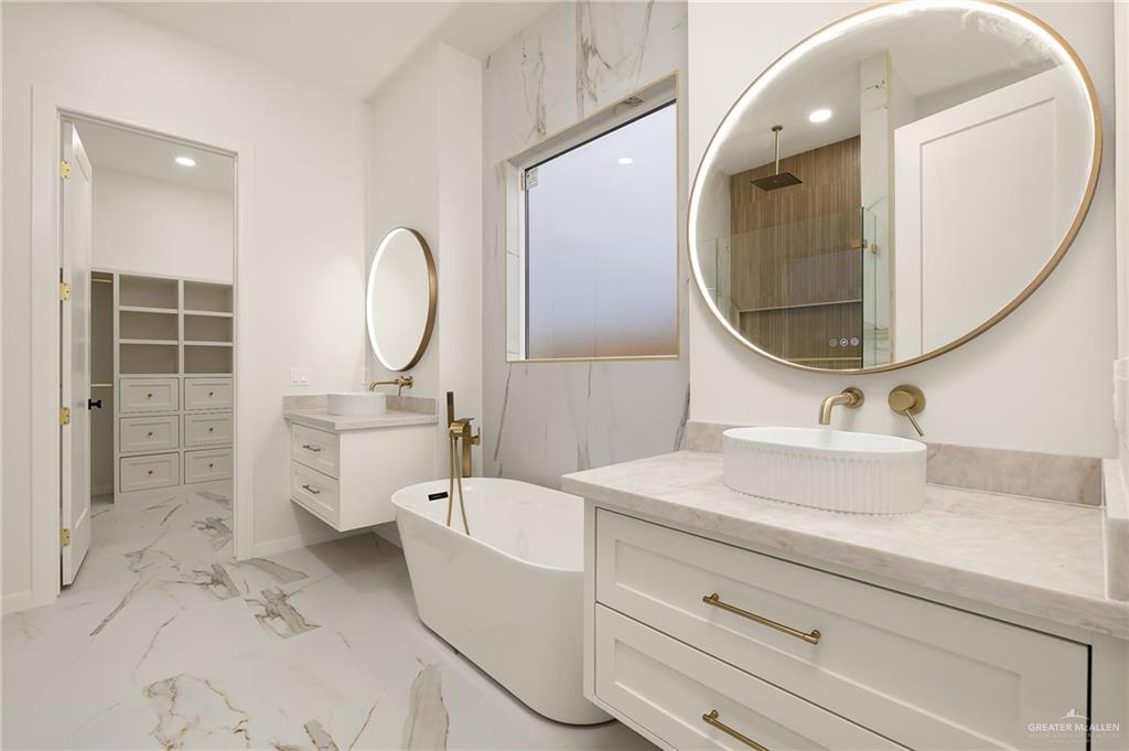 1107 Benjamin Street Mission, TX 78573 - Photo 12 of 19 Bathroom featuring a freestanding tub, dual vanities with vessel sinks, and an illuminated mirror