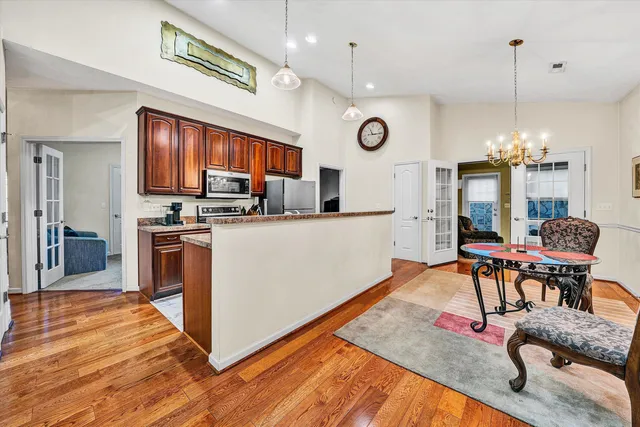 a kitchen with stainless steel appliances granite countertop a stove top oven a refrigerator a sink dishwasher a dining table and chairs with wooden floor