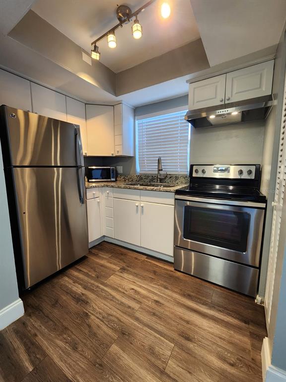 701 1st Street, Unit 4 Indian Rocks Beach, FL 33785 - Photo 2 of 10 a kitchen with wooden cabinets and stainless steel appliances