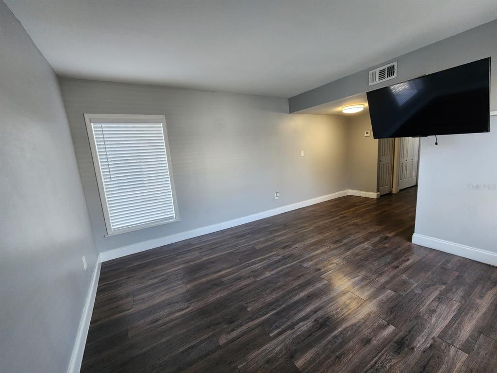 701 1st Street, Unit 4 Indian Rocks Beach, FL 33785 - Photo 3 of 10 an empty room with wooden floor and windows