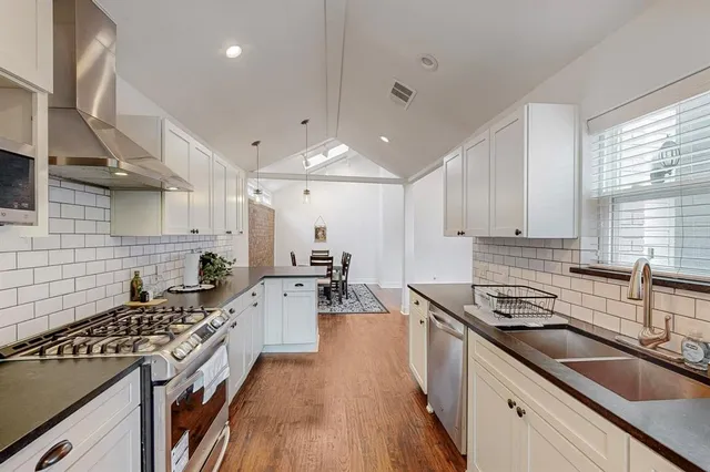 a kitchen with a sink stove cabinets and wooden floor