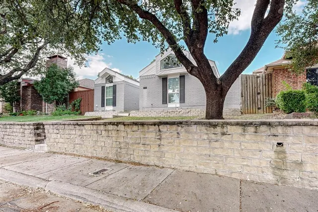 a front view of a house with large trees