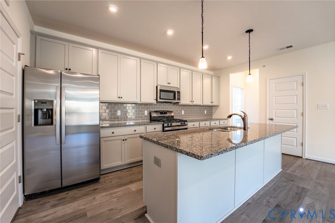 4003 Next Level Trace Midlothian, VA 23112 - Photo 7 of 38 a kitchen with stainless steel appliances granite countertop a refrigerator a sink a stove a microwave and wooden floors