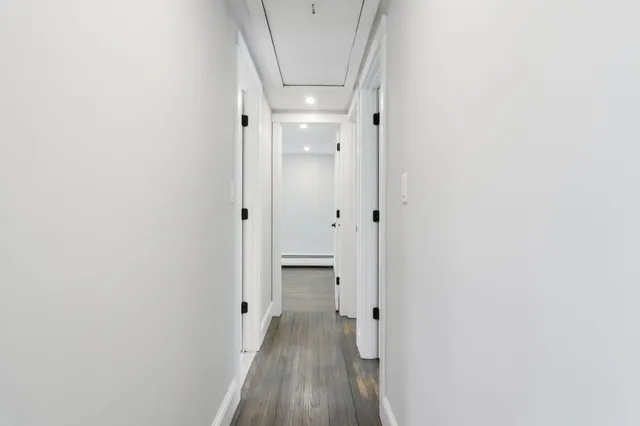 a view of a hallway with wooden floor and a bathroom