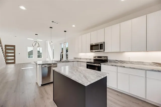 a kitchen with granite countertop white cabinets and stainless steel appliances