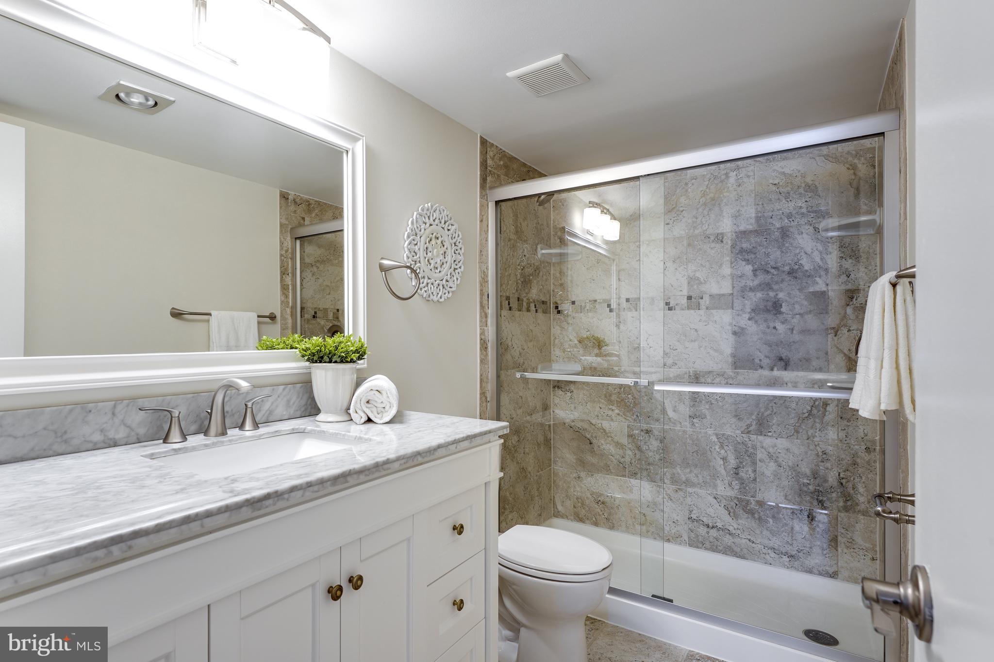 1800 Old Meadow Road, Unit 621 McLean, VA 22102 - Photo 12 of 28 a bathroom with a granite countertop sink a toilet a mirror and shower