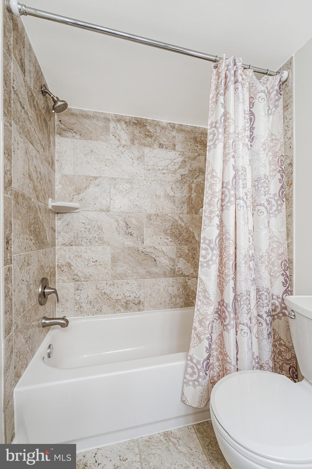 1800 Old Meadow Road, Unit 621 McLean, VA 22102 - Photo 16 of 28 a white bath tub sitting next to a white toilet and curtain