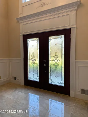a hallway with wooden floor chandelier and entryway