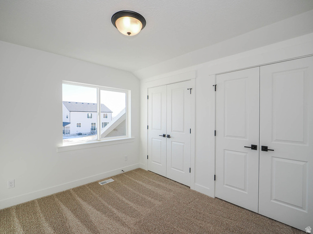 3938 North Wood Road Eagle Mountain, UT 84005 - Photo 36 of 55 Unfurnished bedroom with two closets, carpet floors, and lofted ceiling