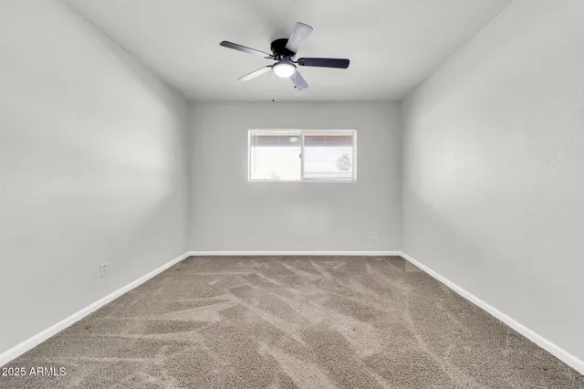an empty room with a window and a ceiling fan
