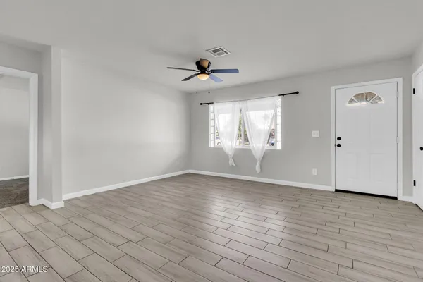 a view of an empty room with wooden floor and a window