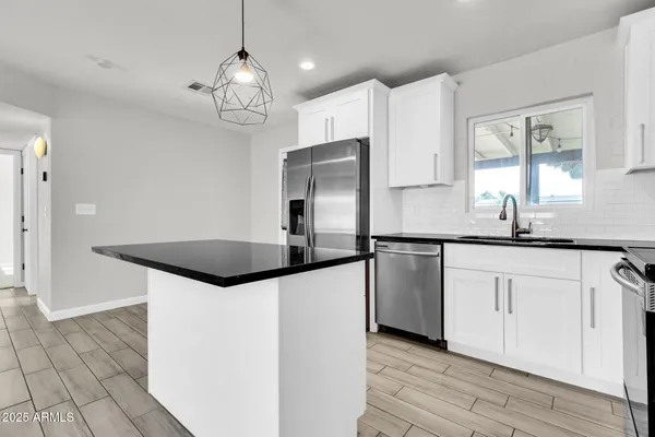 a kitchen with granite countertop a sink cabinets and stainless steel appliances