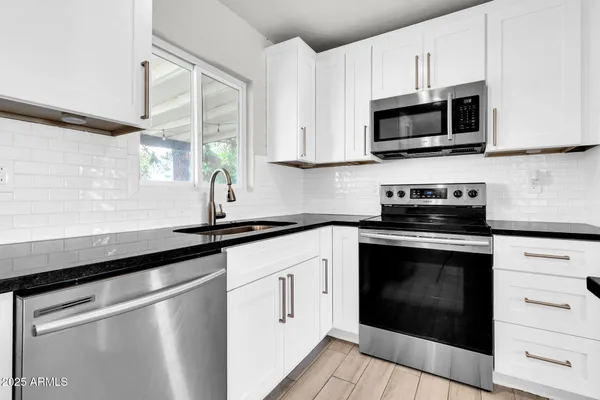 a kitchen with white cabinets stainless steel appliances and sink
