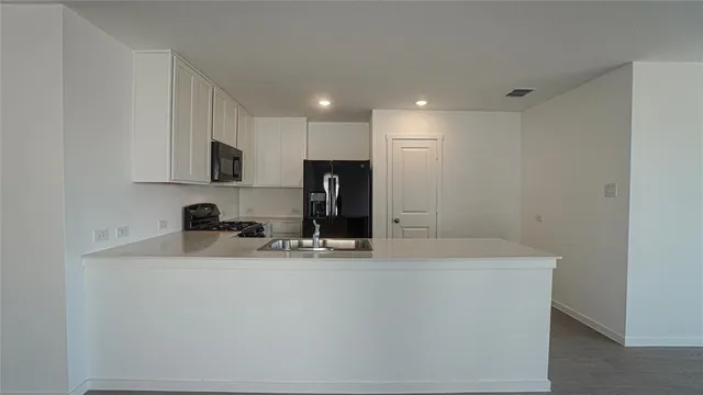 a kitchen with kitchen island a sink stainless steel appliances and white cabinets