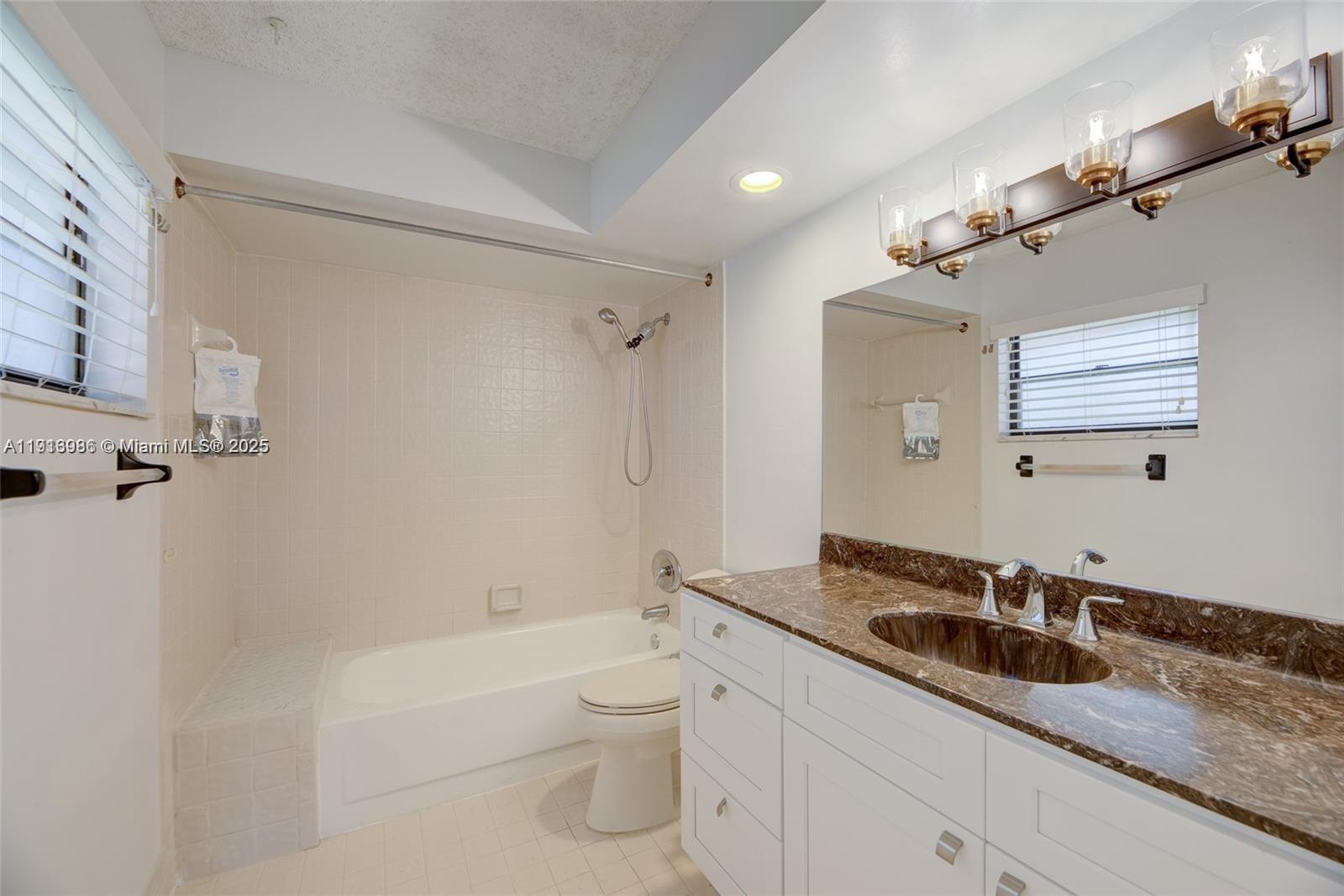 31 Cortez Way, Unit 543 Davie, FL 33324 - Photo 20 of 36 a bathroom with a granite countertop sink a toilet a mirror and shower