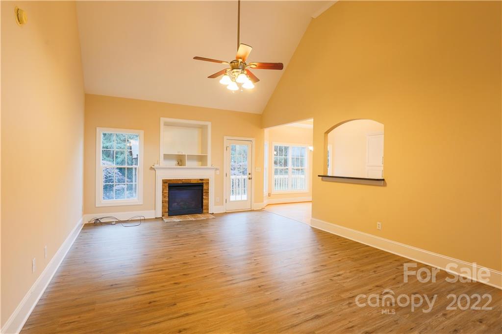 142 Princess Loop Troutman, NC 28166 - Photo 3 of 22 a view of a livingroom with wooden floor a ceiling fan and a fireplace