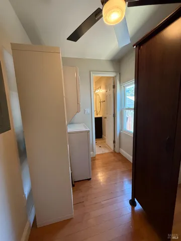 a view of a hallway to room with wooden floor and cabinet