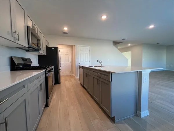 a kitchen with stainless steel appliances a sink a stove top oven a refrigerator with wooden floors and cabinets