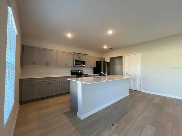 a large kitchen with stainless steel appliances granite countertop a large counter top a sink dishwasher a stove and a refrigerator with wooden floor