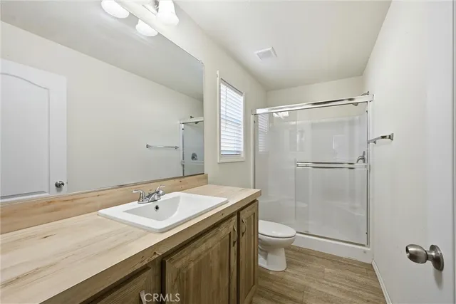 a bathroom with a sink a toilet a mirror and shower