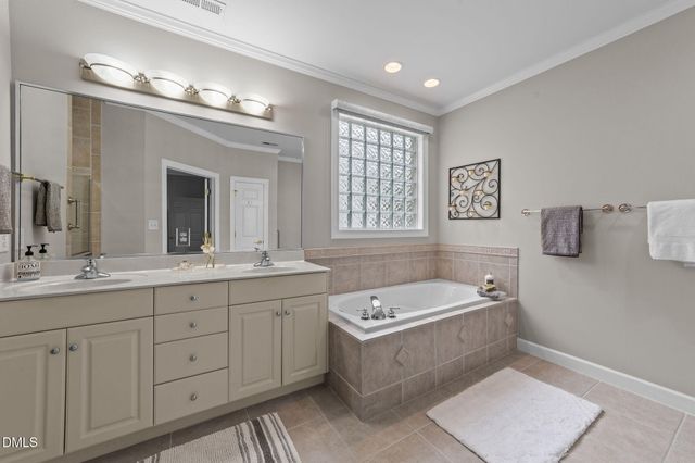 a bathroom with a tub a double vanity sink a window a mirror and